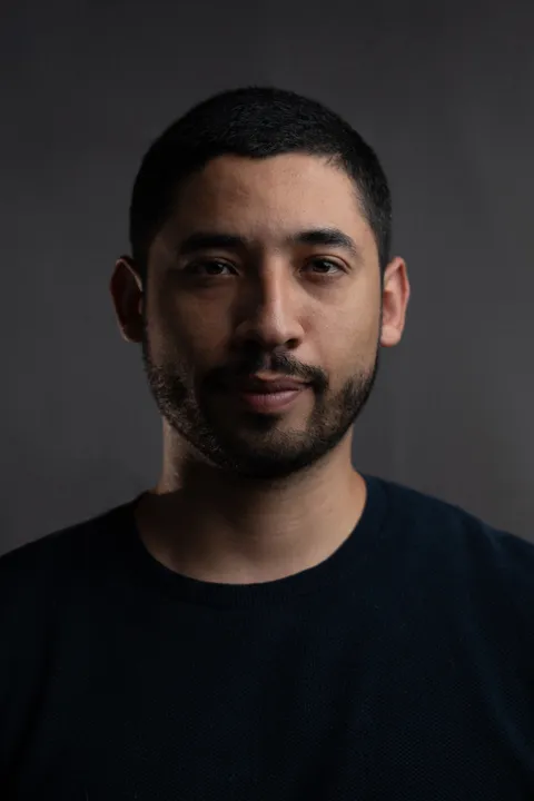 Close studio portrait in a dark shirt against a gray backdrop