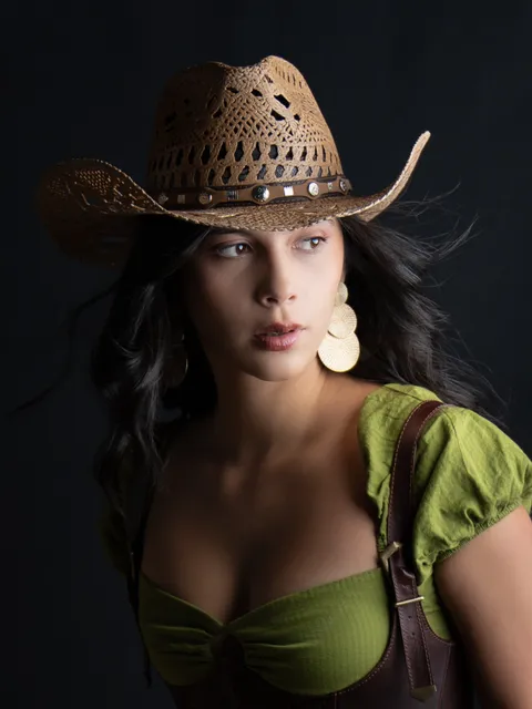 Close portrait in a straw cowboy hat and green dress, looking to one side