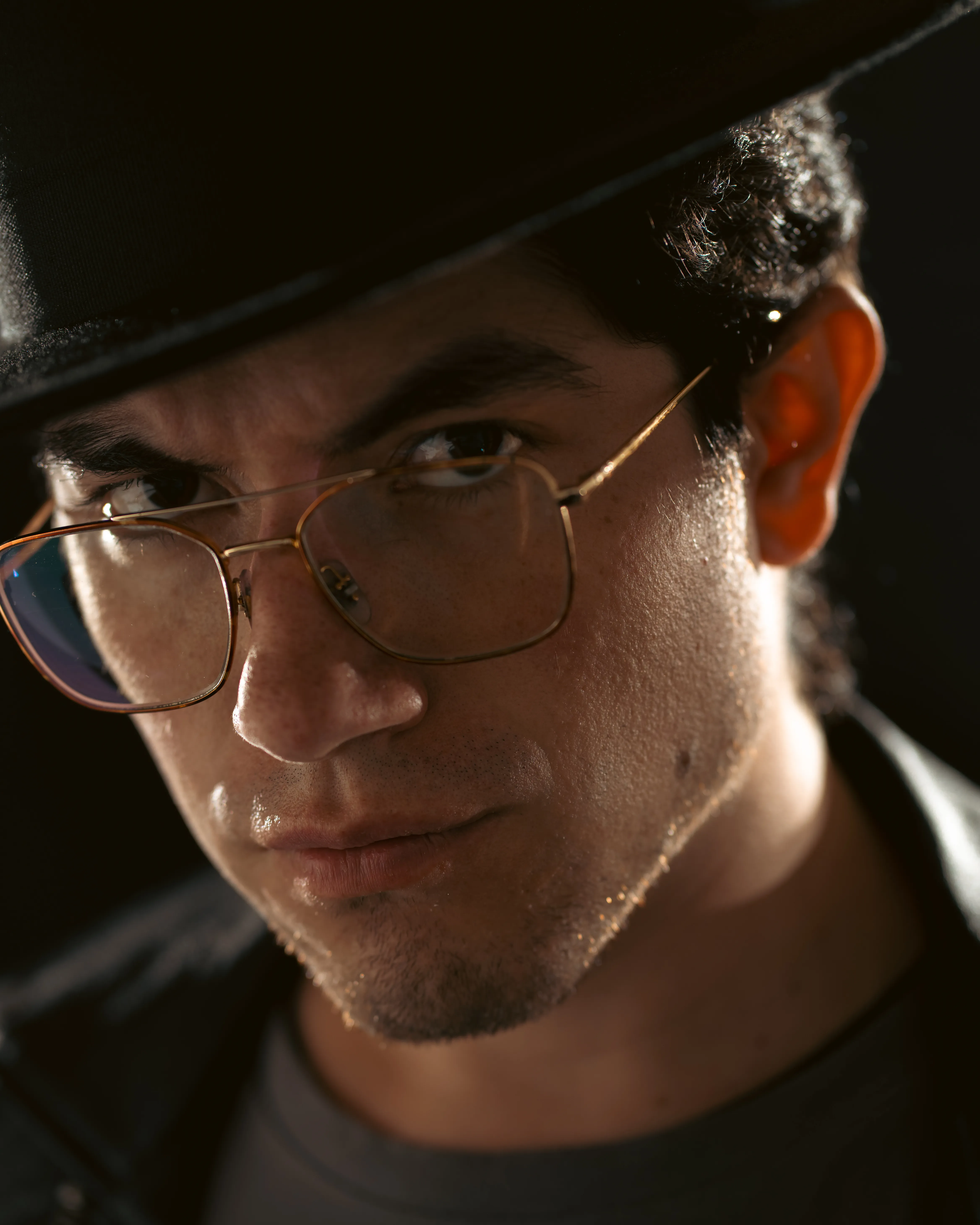A close portrait of a man in a dark cap with warm light on his face.