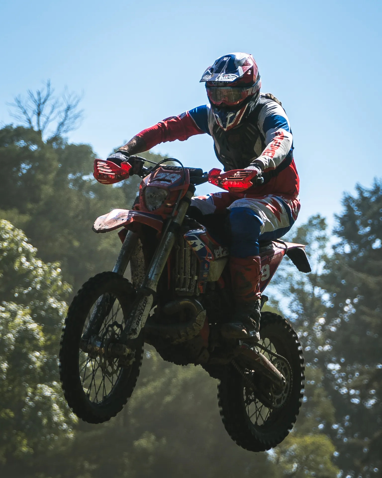 A rider and motorcycle are suspended in the air against a blue sky.