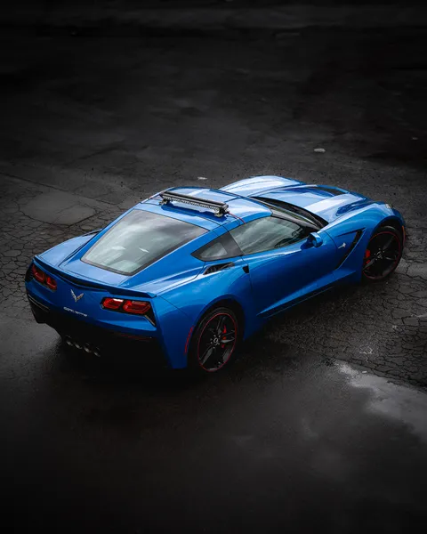 Blue Corvette seen from above on dark pavement
