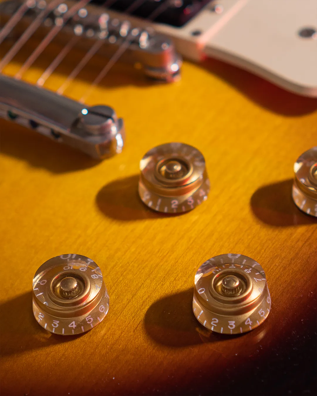A close view of amber guitar controls and metal strings.
