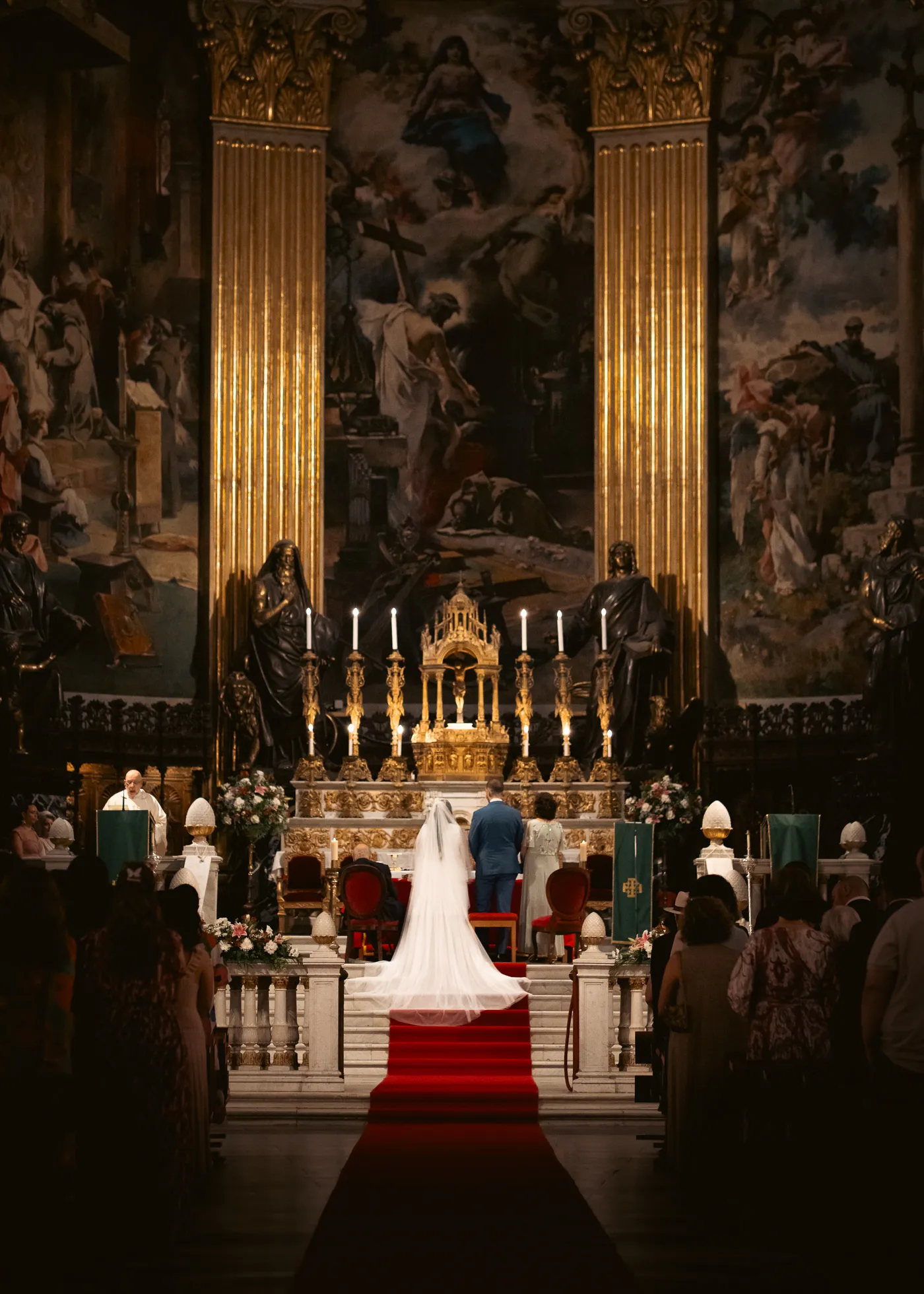 People stand before a candlelit altar in an ornate church interior.