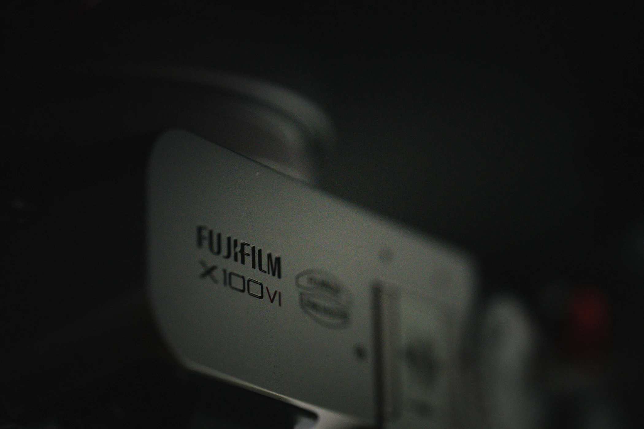 A Fujifilm X100VI camera emerging from deep shadow