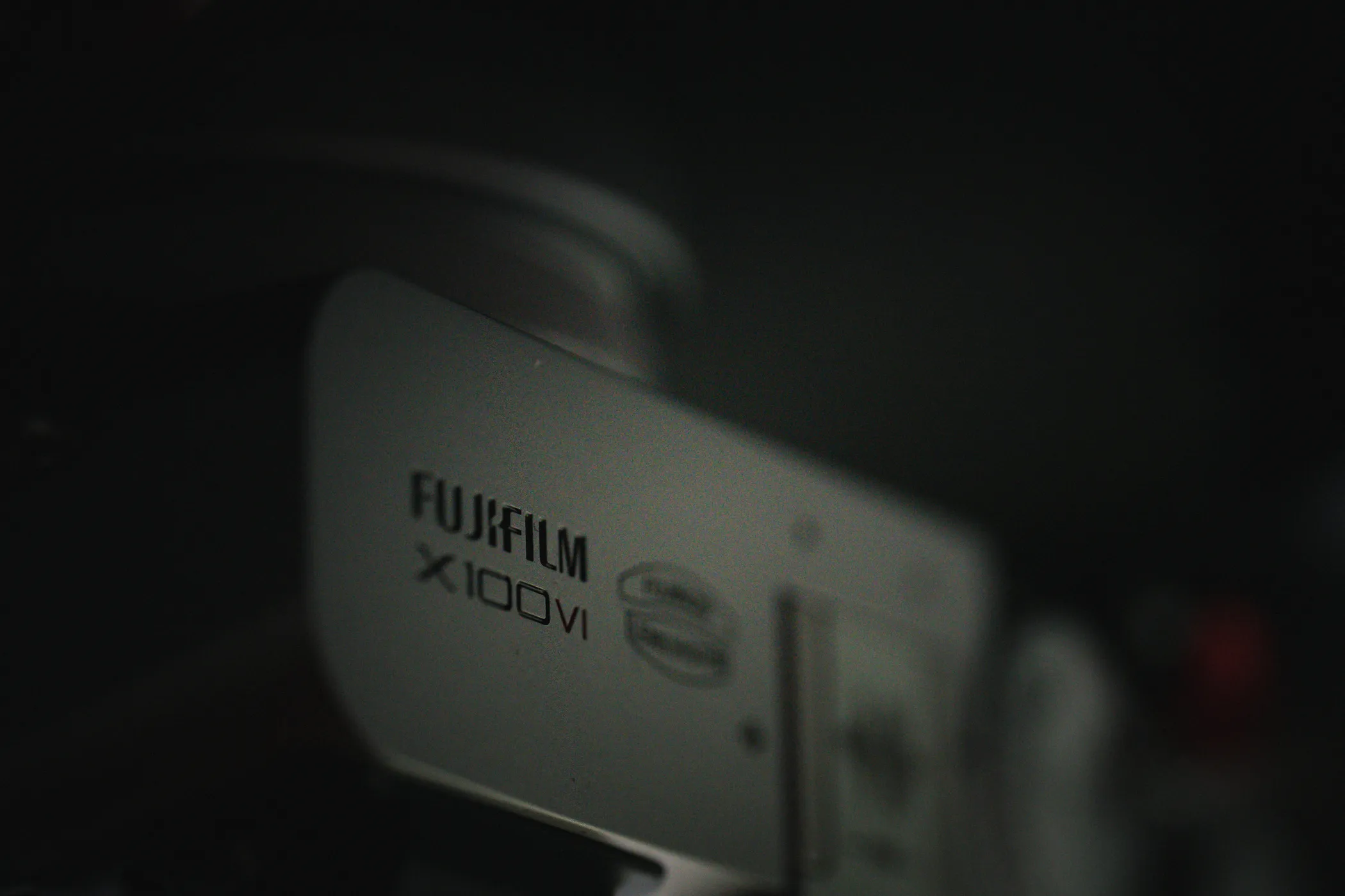 A Fujifilm X100VI camera emerging from deep shadow